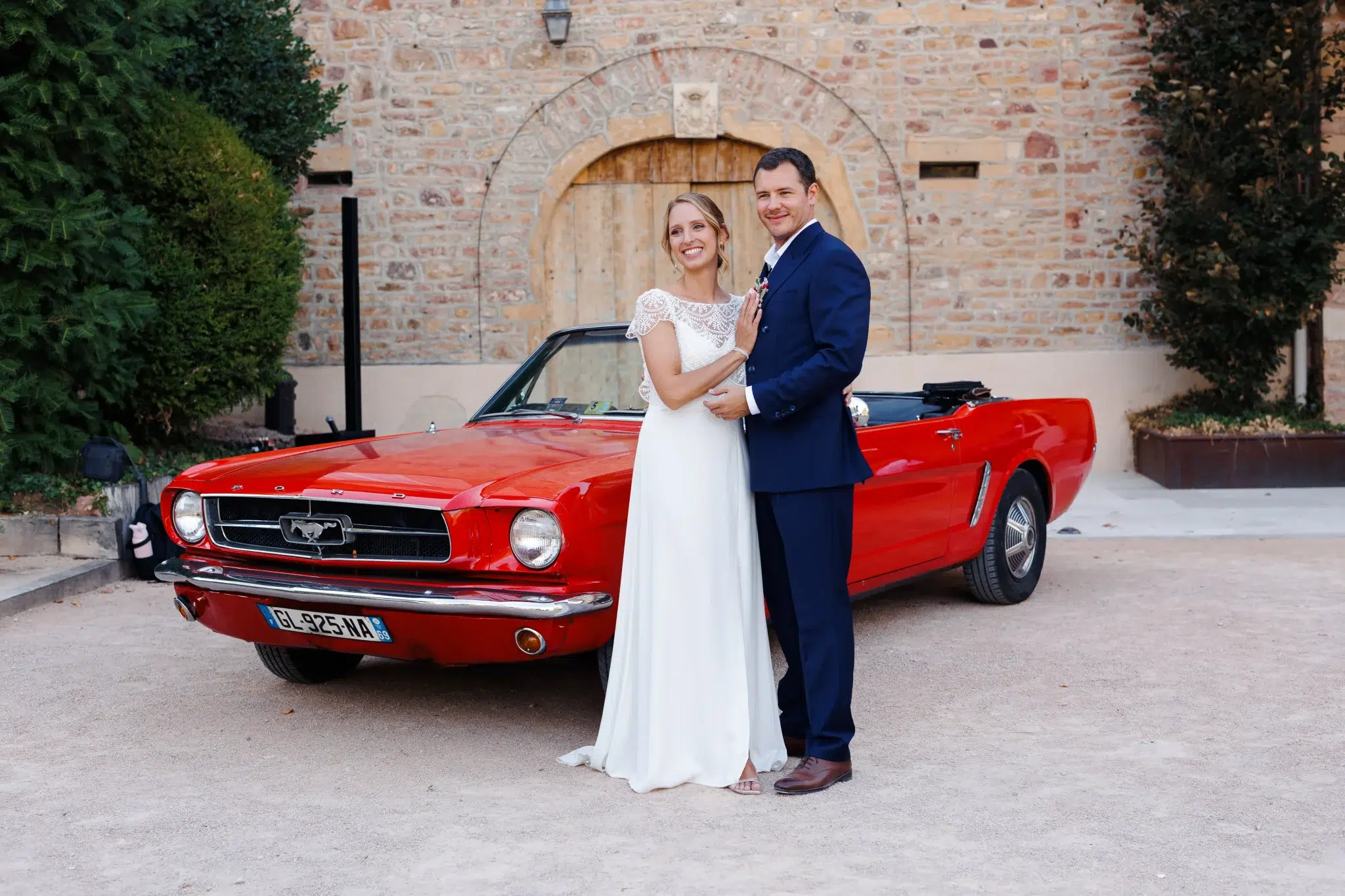 couple de mariés devant une voiture